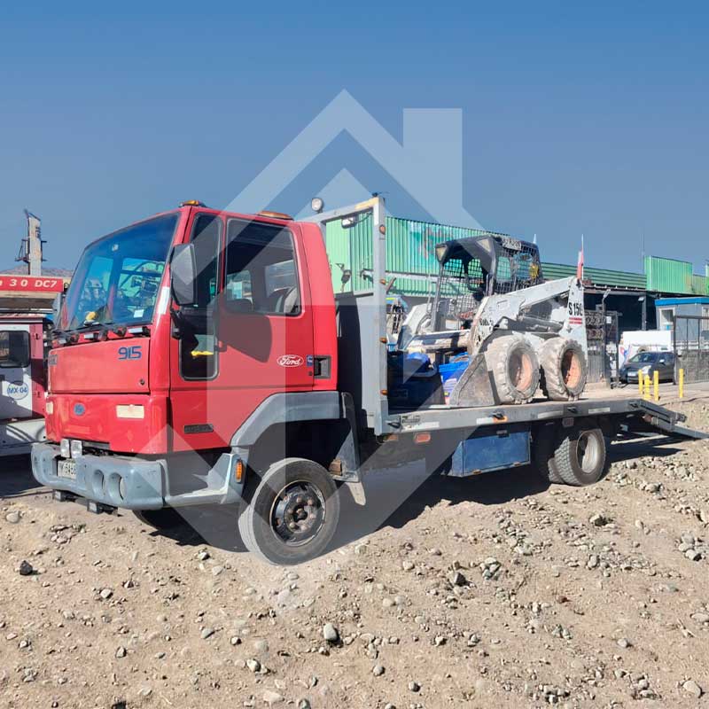 Miniexcavadora sobre camión con amarras.