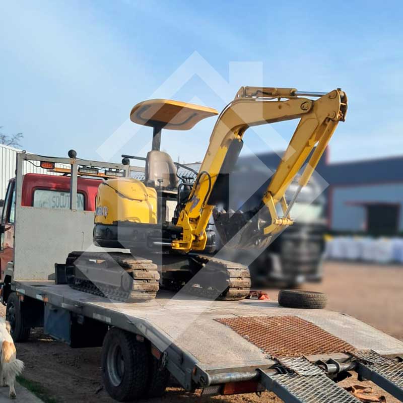 Miniexcavadora sobre camión sin amarras.